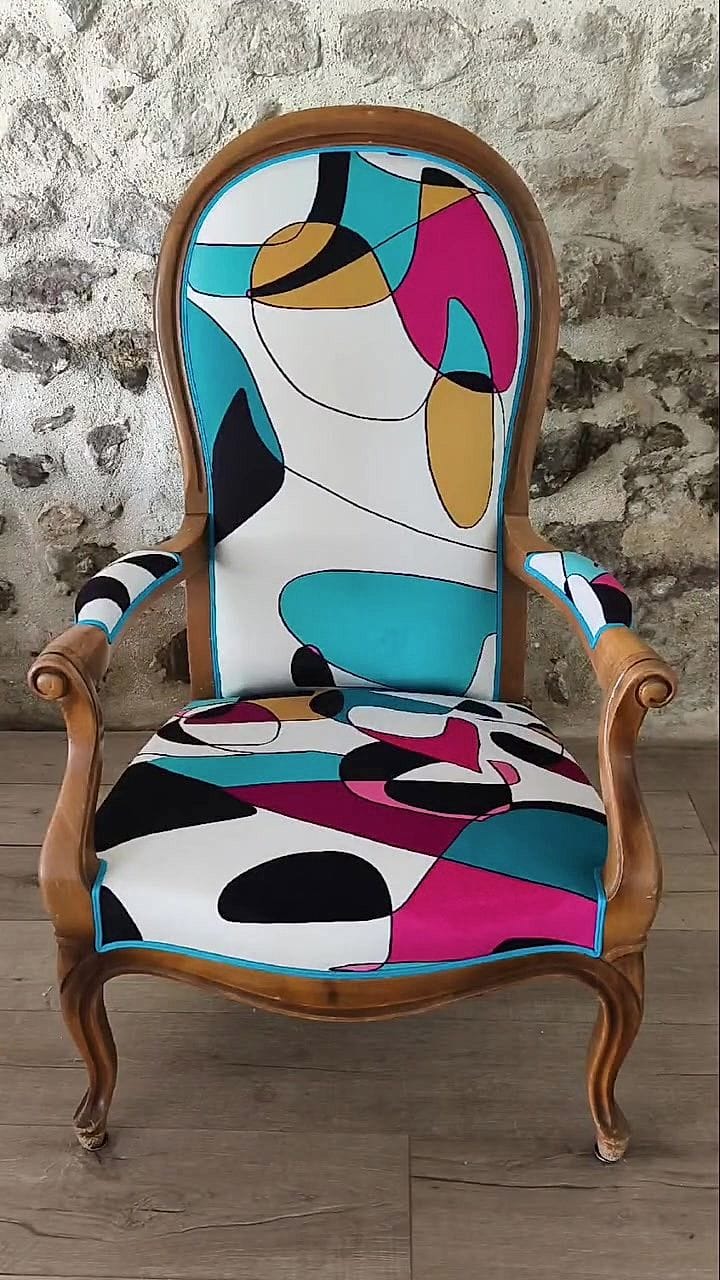 Fauteuil Voltaire recouvert d&rsquo;un tissu abstrait aux aplats roses, bleus et noirs