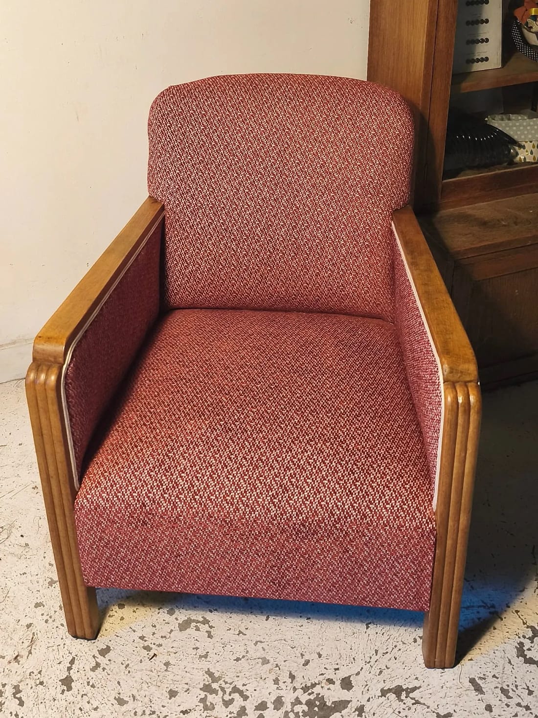 Fauteuil club recouvert d&rsquo;un tissu terre cuite, devant un mur de pierre