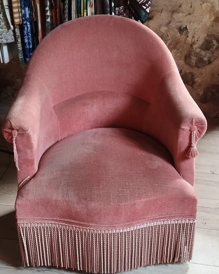 Fauteuil crapaud recouvert d&rsquo;un velours rose, frange de finition au sol