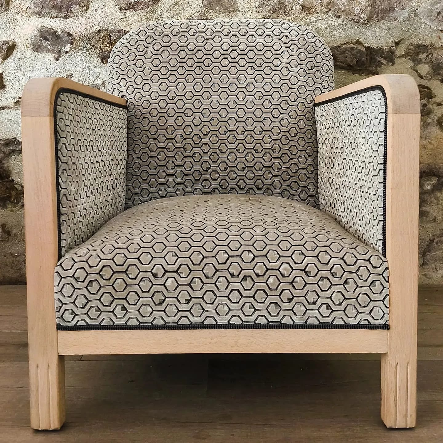 Fauteuil en bois clair recouvert d&rsquo;un tissu à motif géométrique