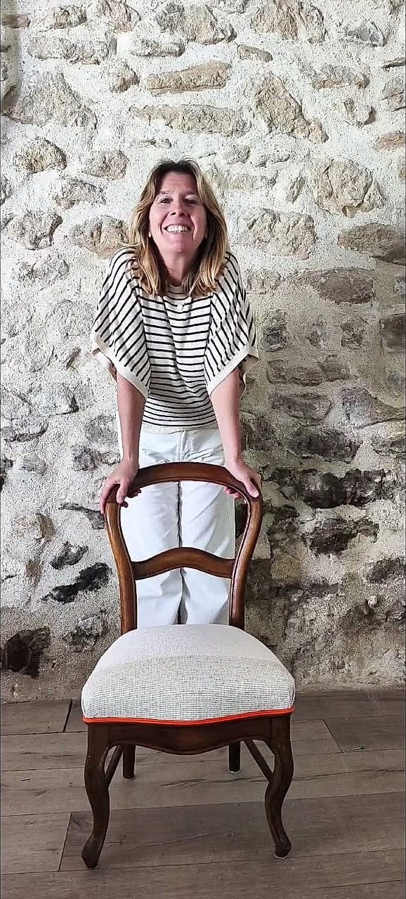 Nathalie Desreumaux derrière une chaise qu&rsquo;elle vient de terminer, dans son atelier